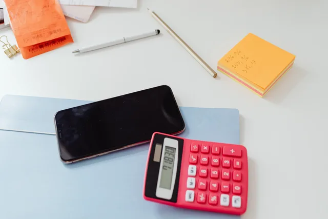 An organized office desk featuring a calculator, smartphone, and sticky notes on a white surface. Meta product catalogues for UK retailers: common feed errors