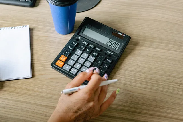 A person uses a calculator and pen on a wooden surface, focusing on office work. Which Shopify product feed plugin works best for UK Google Shopping?