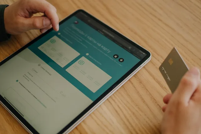 Hands making an online purchase using a tablet and credit card on a wooden table. Why a shopping feeds operating workflow beats firefighting